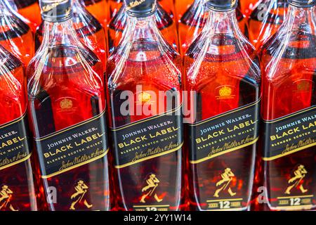 Close-up view of Johnnie Walker Black Label blended scotch whisky bottles with red reflections on store shelf. Sweden. Stockholm. Stock Photo