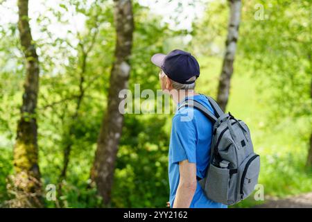 Senior man with backpack hiking in the forest. Travel and active lifestyle concept. Active backpacking travel concept Stock Photo