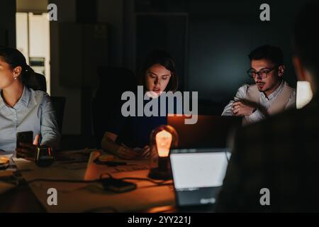 A diverse group of colleagues collaborate late into the night, focused on meeting tight deadlines Stock Photo