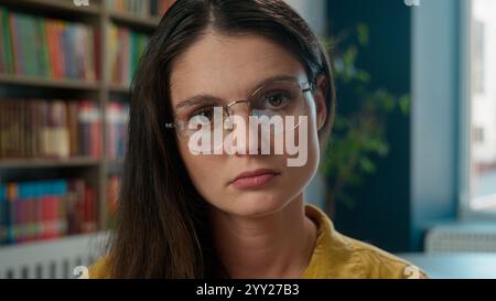 Sad worried tired exhausted girl Caucasian woman high school student teacher helpless stressful books studying learning college university library Stock Photo