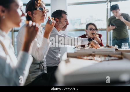 A diverse group of business colleagues take a break to enjoy pizza during a work meeting. Stock Photo