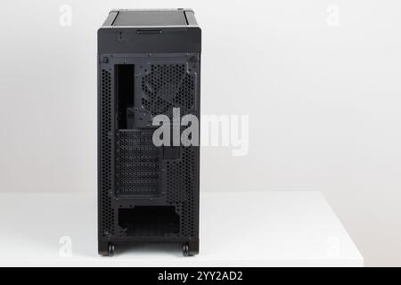 Back side of empty  big  tower computer case, chassis , effortless maneuvering with two built-in  wheels on white background. At the bottom is a place Stock Photo