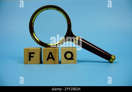 FAQ with wooden blocks alphabet letters and Magnifying glass on blue background Stock Photo