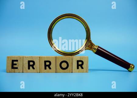 Error with wooden blocks alphabet letters and Magnifying glass on blue background Stock Photo