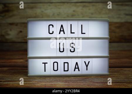 CALL US TODAY letterboard text on LED Lightbox on wooden background, Business and Communication concept background Stock Photo