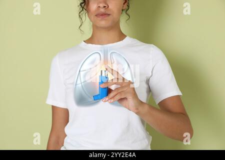 Woman holding asthma inhaler on color background, closeup. Illustration of lungs Stock Photo