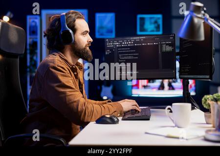 Computer scientist listening audiobooks while securing company servers from malware attacks. IT remote worker at home enjoying podcasts and building firewalls protecting data Stock Photo