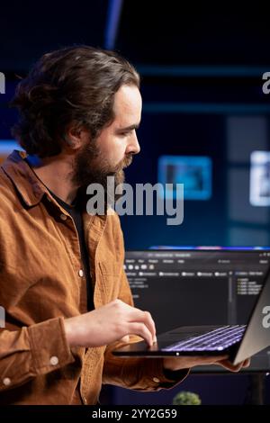 Computer engineer crosschecking between laptop and monitor, implementing security measures to protect company systems. IT worker comparing software code between notebook and PC Stock Photo