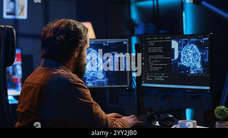 Developer updating artificial intelligence neural networks, typing on computer keyboard in neon lit personal office. Freelancing IT specialist writing AI code, training machine learning, camera A Stock Photo
