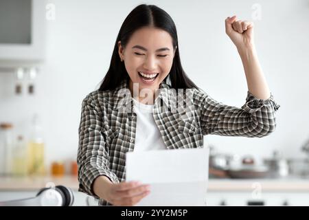 Emotional asian lady celebrating success, reading invitation letter Stock Photo