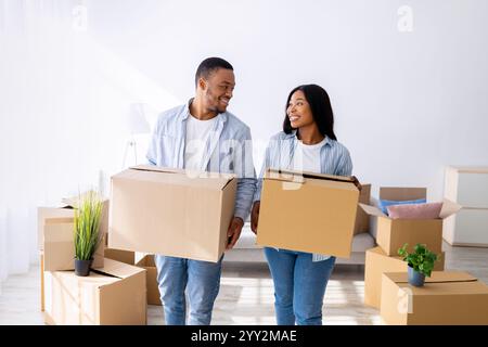Relocation and apartment rent. Loving african american spouses carrying paper boxes into new house Stock Photo