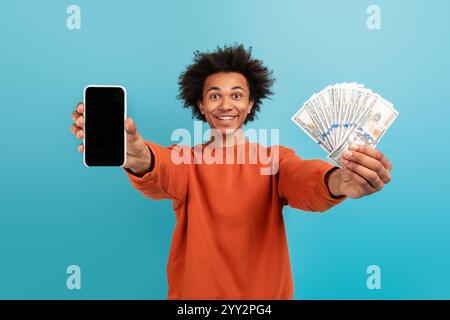 Young man celebrating financial success with cash and smartphone Stock Photo