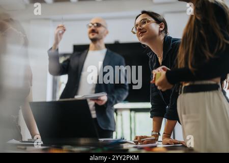 Students collaborating with professor on academic project in classroom Stock Photo