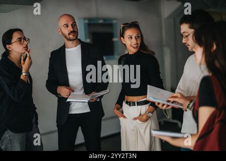 Students engaging with professor in university hallway discussion Stock Photo