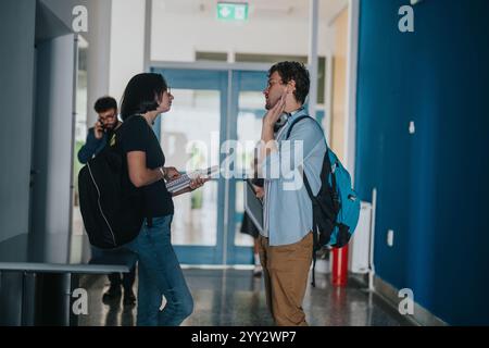 Students engaging with professor in university hallway discussion Stock Photo