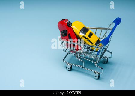 Toy cars inside mini shopping cart on blue background Stock Photo