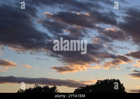 scattered clouds dark below and white above at sunset Stock Photo