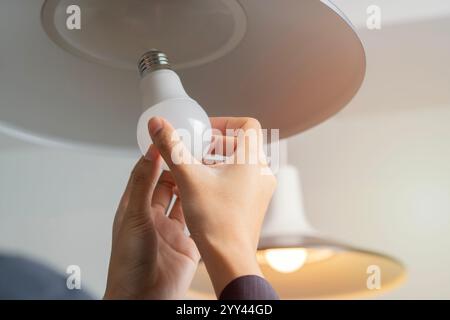 Cropped image of woman hands changing light bulb in hanging lamp at home. Moving, electricity and repair concept Stock Photo