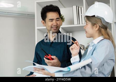 Professional Engineers Discussing Architectural Plans in Modern Office Setting with Blueprints and Safety Gear Stock Photo