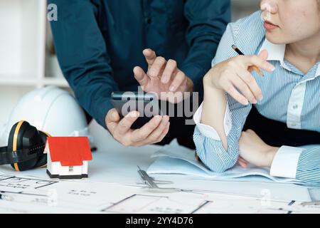 Engineers Collaborating on Architectural Design Plans with Modern Technology and Construction Tools Stock Photo