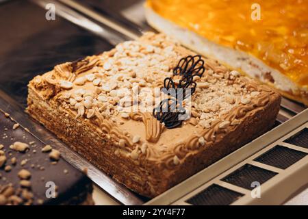 A tantalizing selection of pastries showcased in a shop window, featuring layered cakes with creamy toppings and chocolate decorations Perfect for a s Stock Photo