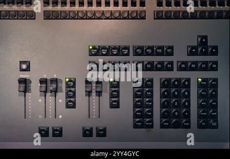 Close-up of a control panel featuring numerous buttons and faders, used in professional sound or lighting setups. Perfect for illustrating audio or st Stock Photo