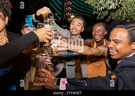 A lively group of friends celebrating together at a city nightlife scene They are smiling and toasting with drinks, enjoying the festive atmosphere an Stock Photo