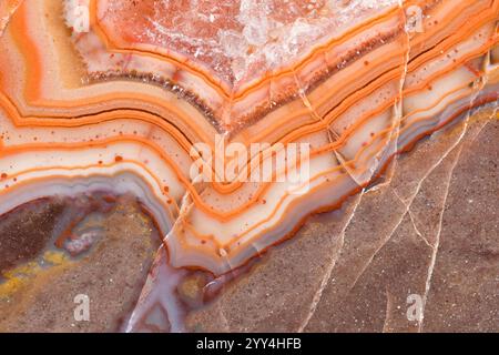 A close-up of vibrant stone layers showcasing intricate patterns in orange, white, and brown hues. The image highlights natural textures and earthy to Stock Photo