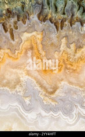 A detailed view of a natural stone surface showcasing earthy tones and intricate patterns. The swirling lines and colors evoke a sense of fluidity and Stock Photo
