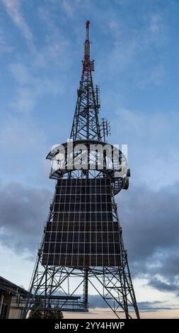 Close-up view of the communication tower at La Barillette, Switzerland, showcasing its intricate metal structure and solar panels against a serene eve Stock Photo