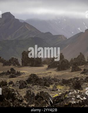 A breathtaking Icelandic landscape featuring rugged volcanic rock formations set against striking mountains shrouded in mist A perfect depiction of ra Stock Photo