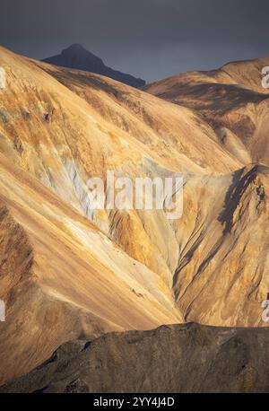 Breathtaking view of Iceland's rugged, golden-brown hills and distant peaks, capturing the raw beauty and dramatic shades under a moody sky, showcasin Stock Photo