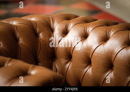 A close-up of a luxurious tufted brown leather sofa, highlighting its texture and rich tone The warm ambient lighting enhances the elegance and comfor Stock Photo