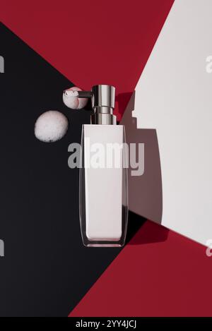 A sleek liquid soap dispenser with a metallic pump on a striking geometric background in red, black, and white, featuring soap bubbles, creating a mod Stock Photo