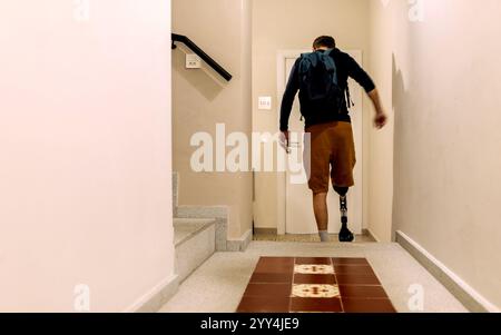 A man with a prosthetic leg walking down a well-lit hallway, carrying a backpack The scene captures determination and everyday life with a mobility ai Stock Photo