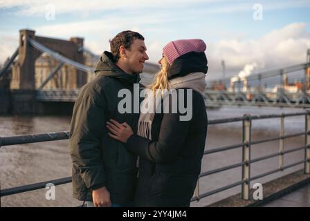A young married couple, enjoys a leisurely stroll in the city of Wroclaw, Poland looking at each other. Both dressed warmly for the cold, they share a Stock Photo