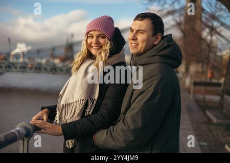 A young married man and woman stroll through Wroclaw, Poland, during the cool season. The woman, smiling warmly at the camera, wears a pink knitted ha Stock Photo
