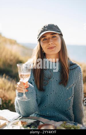 Portrait of beautiful young woman wearing cap while holding wineglass at dinner party Stock Photo