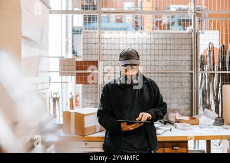 Front view of male warehouse worker using tablet PC while standing in factory Stock Photo