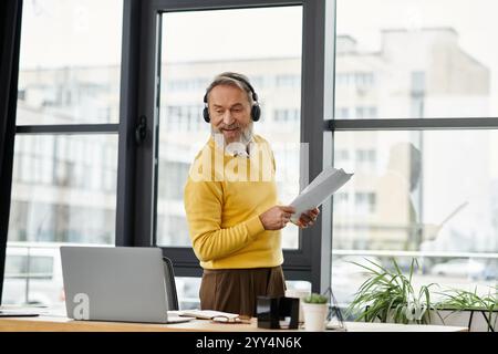 Mature handsome man smiles while reviewing documents at a desk in a bright office setting. Stock Photo