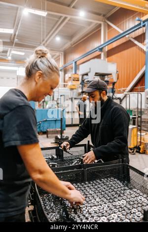 Multiracial female and male employees examining ball bearings in manufacturing factory Stock Photo