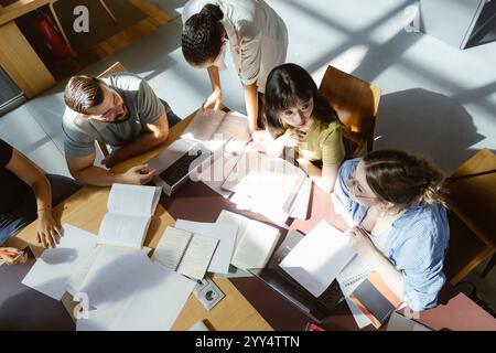 High angle view of multiracial male and female university students doing group assignment in library at college Stock Photo