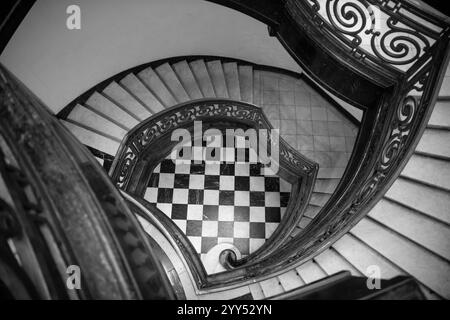 High angle above view down of old vintage staircase winding spiral. Spiral staircase with chess black and white marble floor. Stock Photo