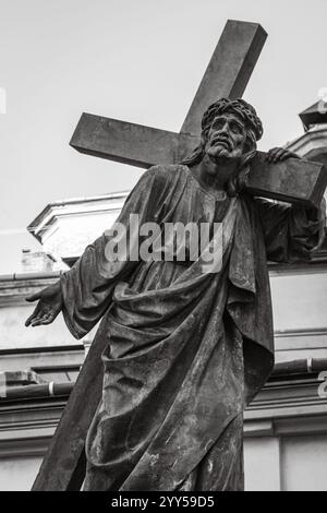 Sculpture of Jesus Christ with cross, black and white. Ancient monument of Jesus Christ in Lviv. Faith and sorrow concept. Old religious statue Stock Photo