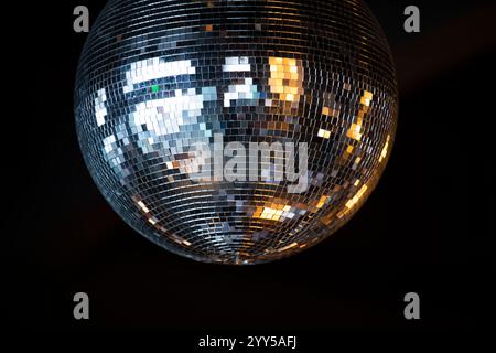 Closeup on shiny disco ball with bright rays against dark background. Stock Photo