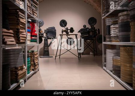 Vintage photo of cinema library with old video movie projectors and film reels on shelves. Stock Photo