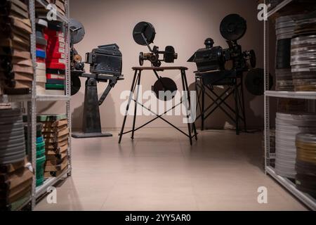 Vintage photo of cinema library with old video movie projectors and film reels on shelves. Stock Photo