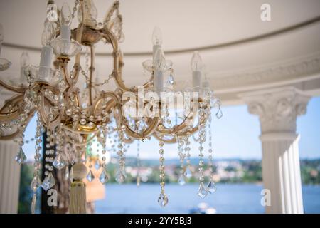 Crystal chandelier luxury style, hanging on the outdoor terrace in the yard. Beautiful classic ceiling lamps and crystals close up. Stock Photo