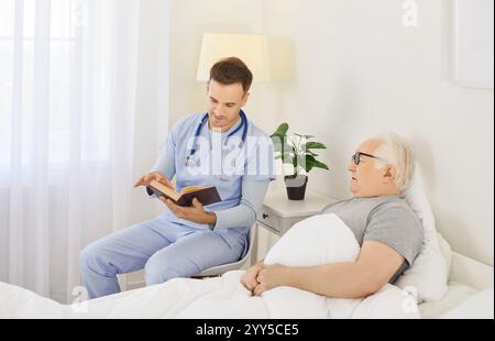 Caregiver Reading Book To Senior Patient During Leisure Time At Nursing Home Stock Photo