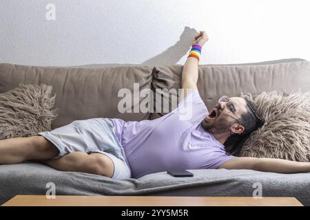 Lazy young man lying on sofa sleepy. Relaxed man lying on the sofa in the apartment. Lazy man lying on a sofa Stock Photo
